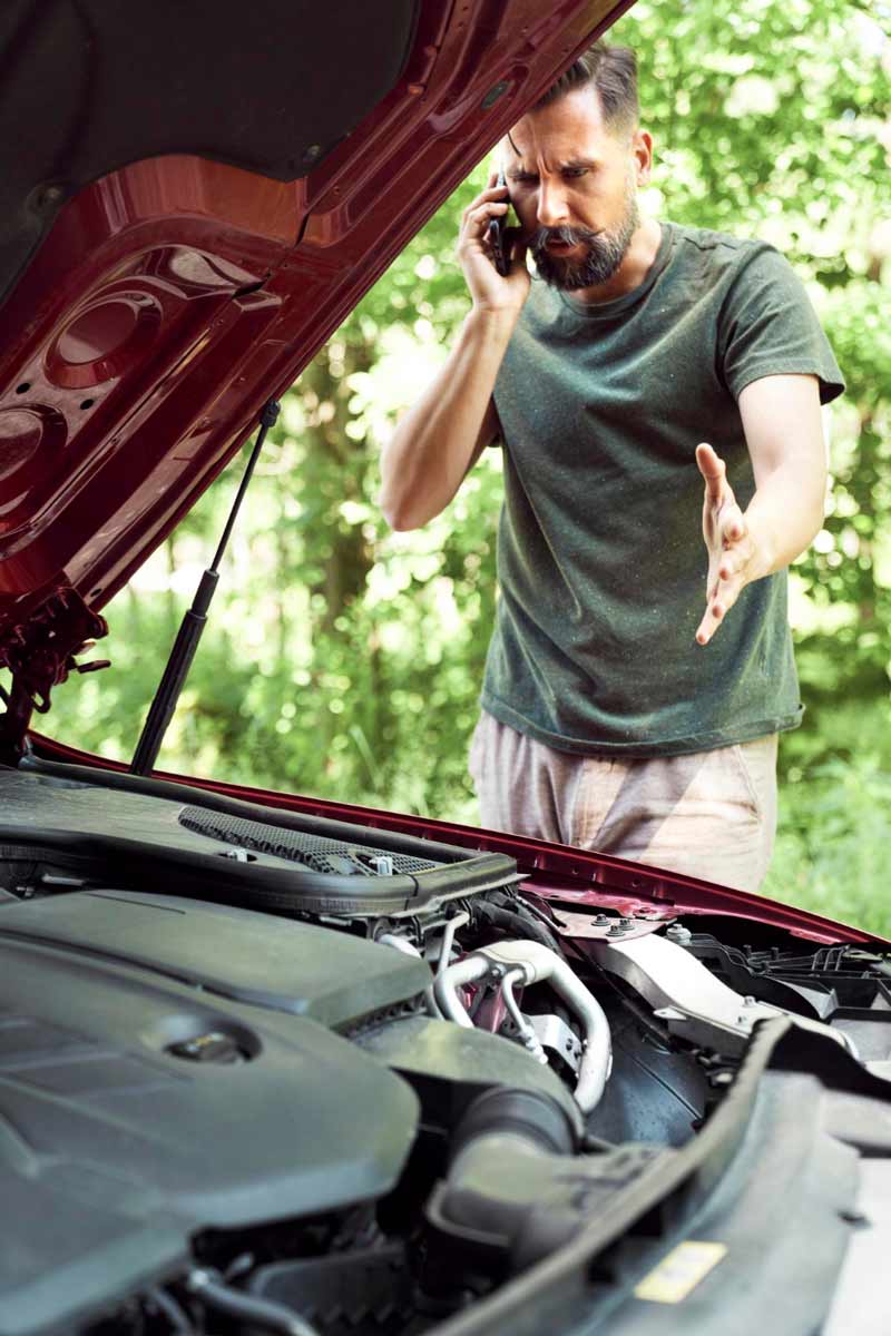 Junger Mann prüft Getriebeschaden bei Schrottauto Ankauf Burgdorf
